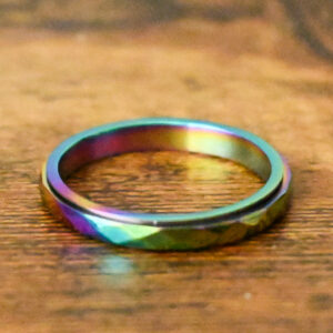 thin faceted spinner ring with rainbow gradient colors on a wood table
