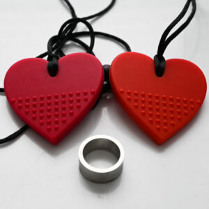 a magenta heart chew necklace, a red heart chew necklace, and an affirmation spinner ring