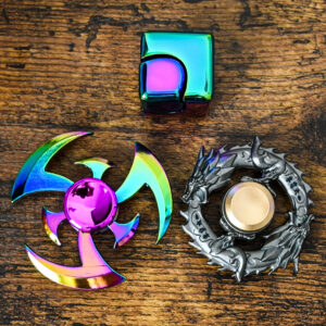 Rainbow fidget cube, rainbow fidget spinner, and a dragon fidget spinner together on a wood table