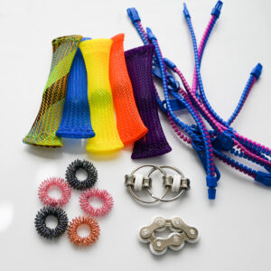 Marble mesh fidgets, 6 pack of blue and purple zipper bracelets, rose rainbow colors acupressure rings, and a white bike chain fidget toy set together on a white reflective surface