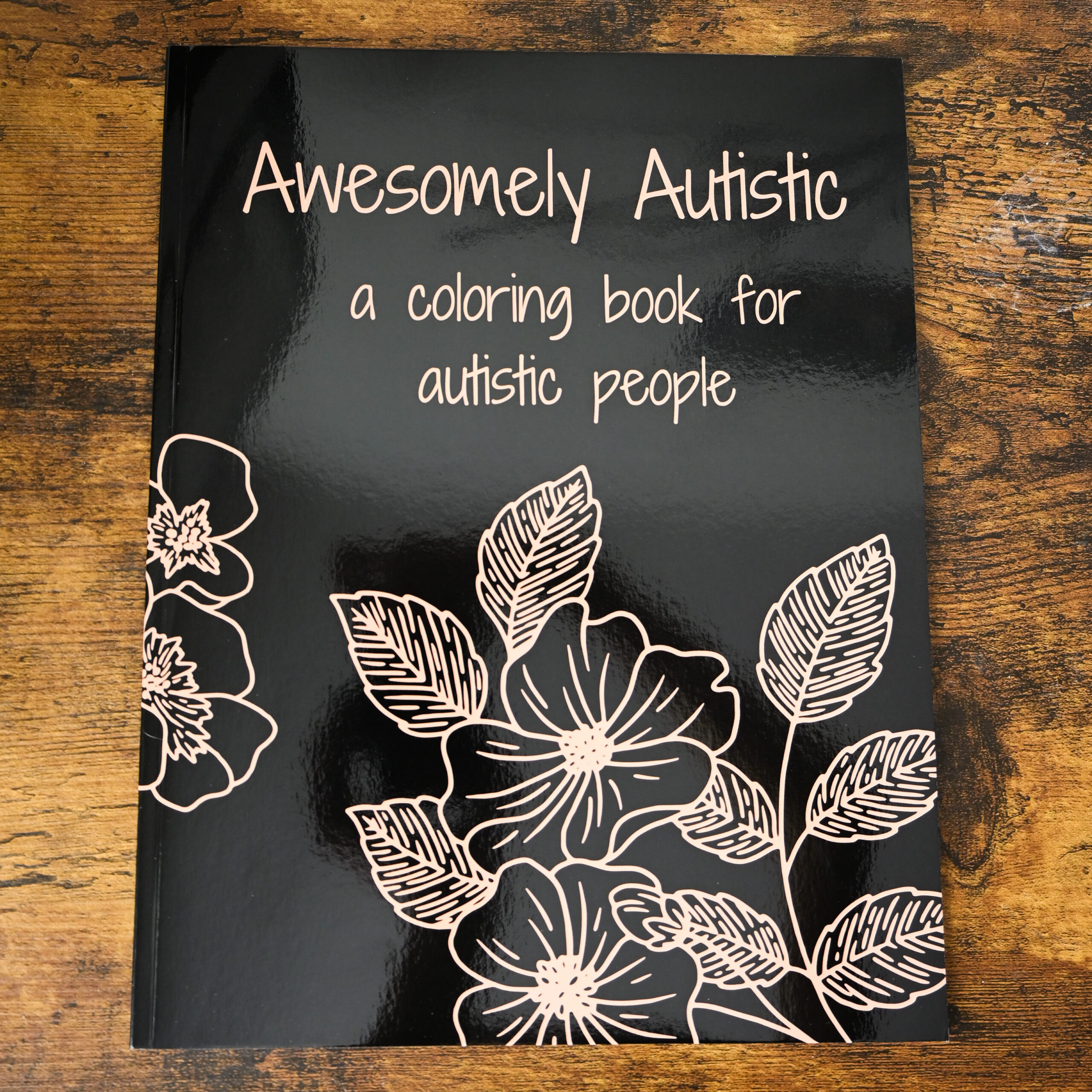 Awesomely Autistic Coloring Book on a wood table