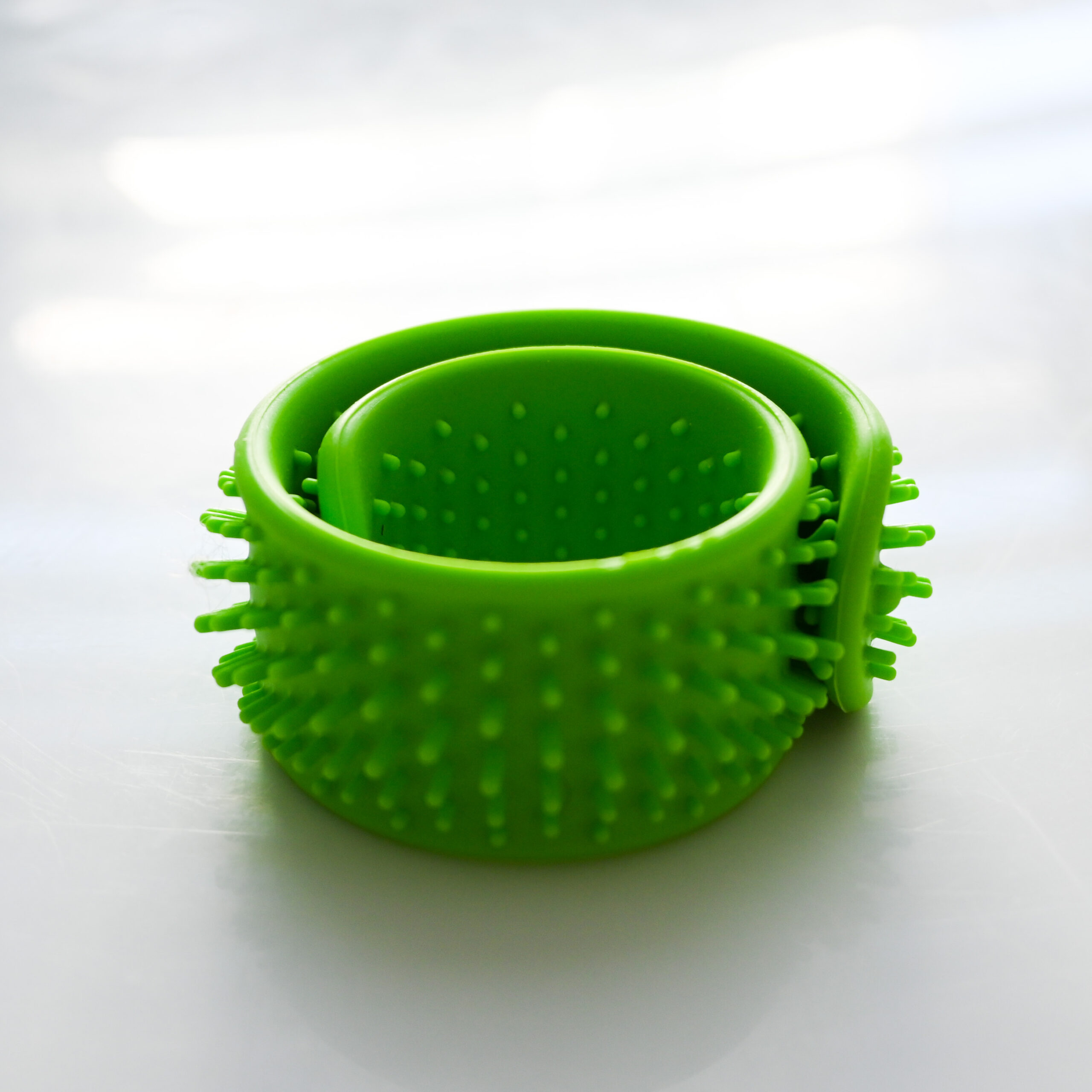 green slap bracelet with soft dull spikes on the outside and short spikes on the inside