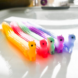 yellow, bright pink, sea green, purple, light blue alpacas standing up side by side. They over blocks of light and shadows. There's a slight vintage film haze.