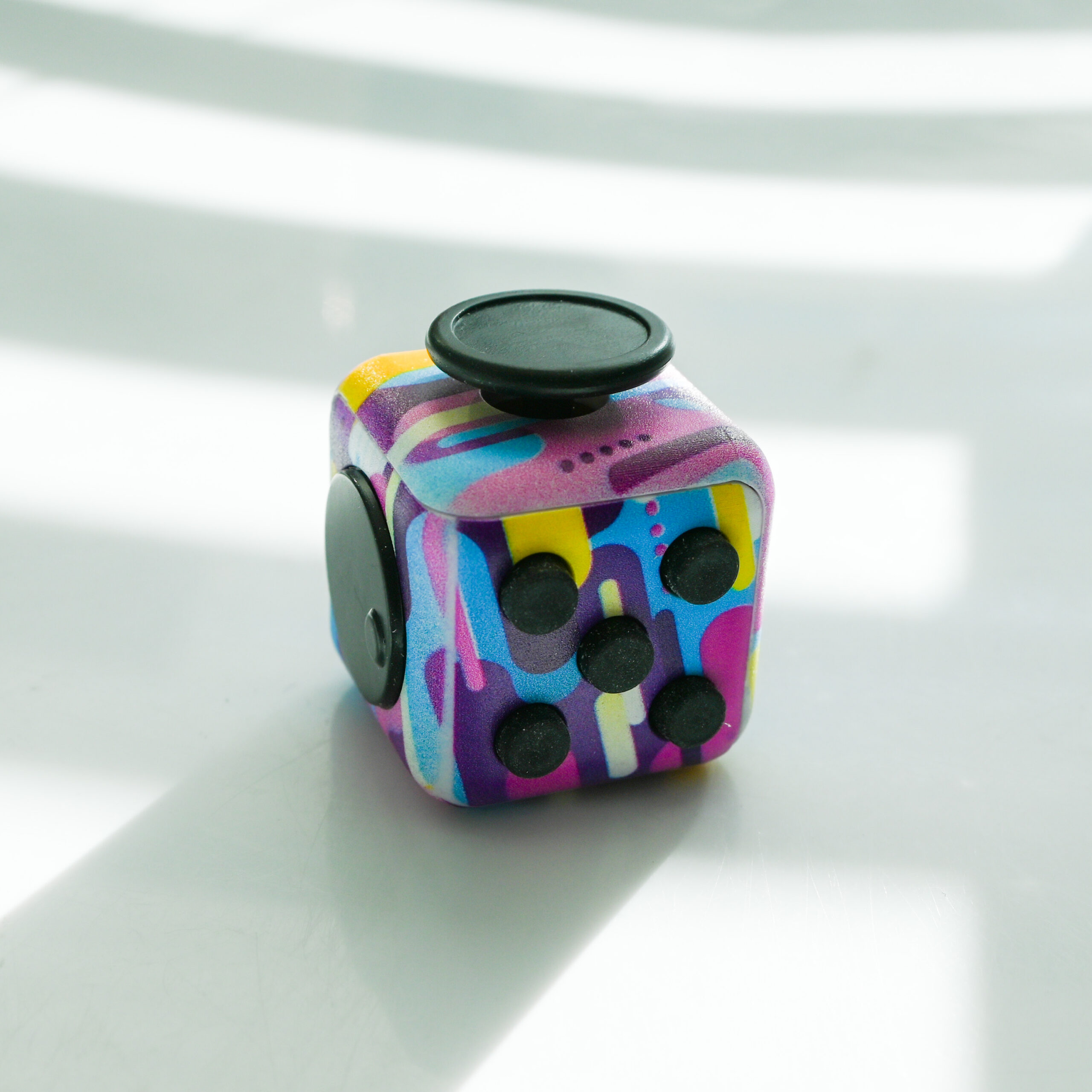 painting print made from pink, light blue, white, pink, yellow fidget with buttons, turn wheel, joystick, switches.