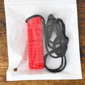 Red colored bar chew necklace inside the bag packaging on a wood table