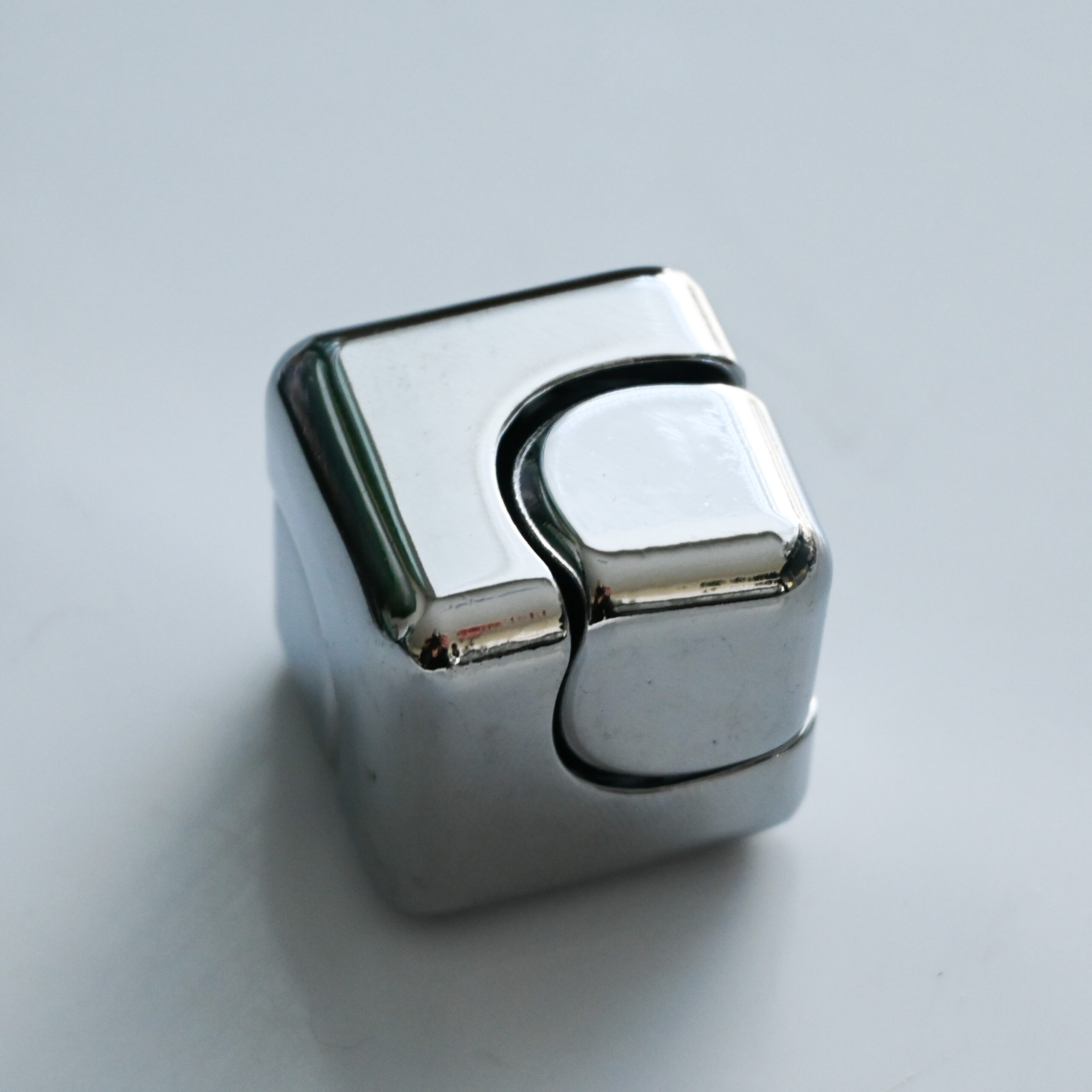 shiny silver metal cube that spins like a fidget spinner