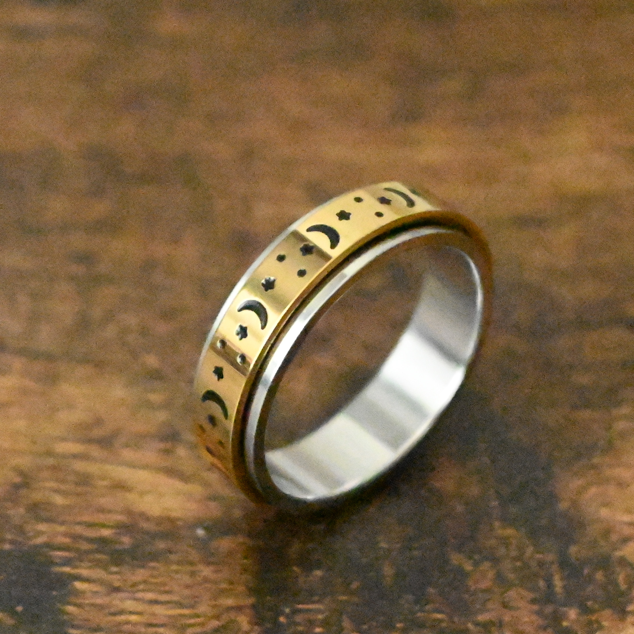 moon and star pattern engraved around a gold spinner on a silver ring