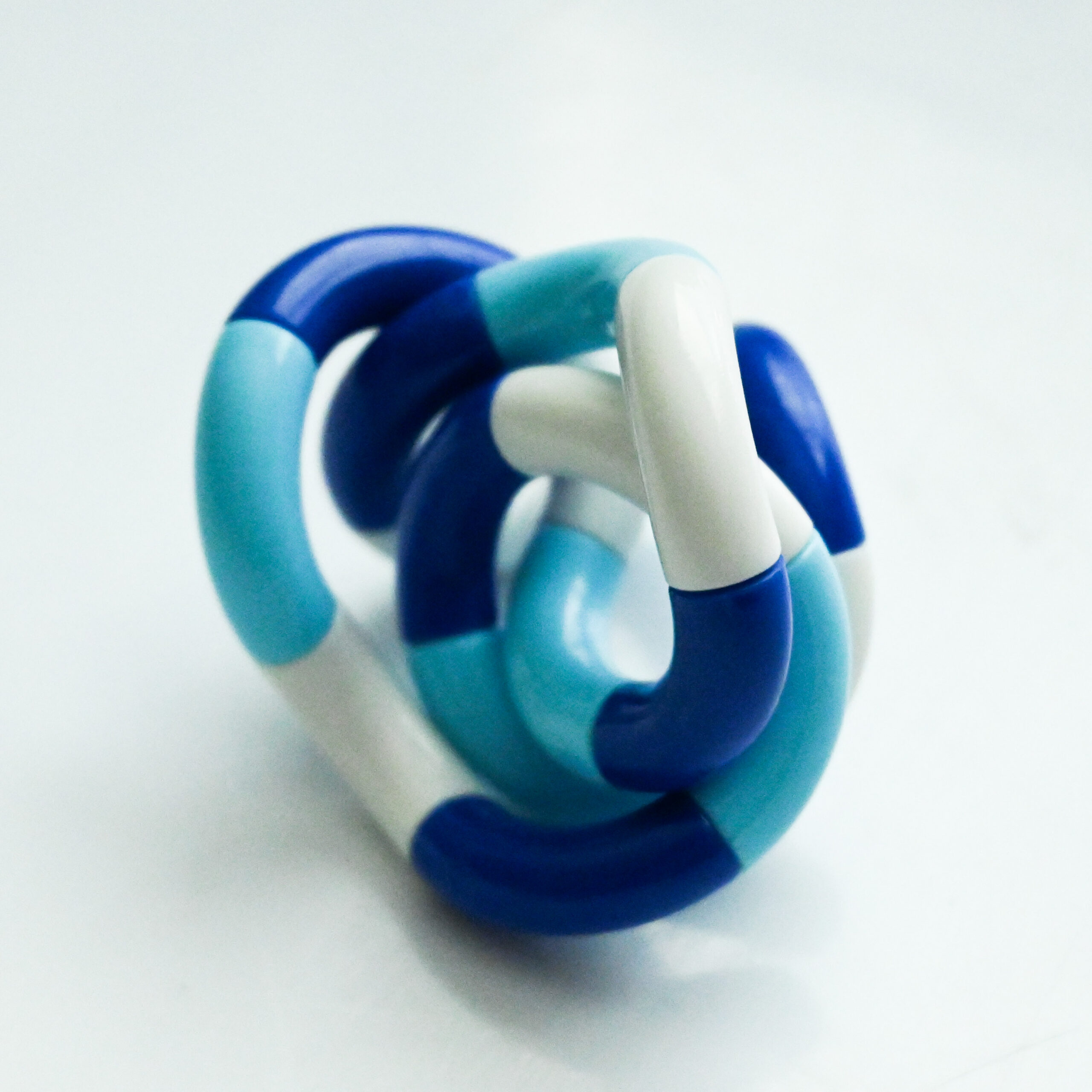 dark blue, light blue, white twisty fidget in a twisted position like a modern art sculpture and a vintage film feel