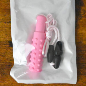 pink textured pendant with a pink necklace string inside the bag packaging on a wood table