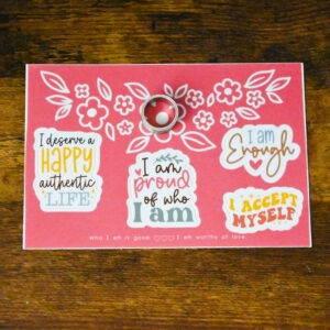 sticker sheet with 4 positive affirmation stickers and the Affirmation Spinner Ring sitting on top of the sticker sheet