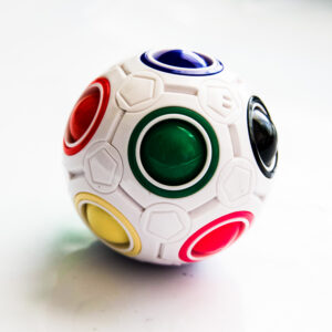 white ball with ball colors inside with dark green, pink, red, black, blue, yellow, and more on the back on a white surface