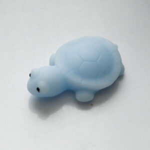 blue turtle squishy on a light grey surface with a turtle shaped shadow underneath the squishy