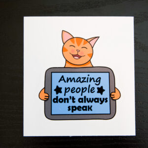 smiling orange cat holding an AAC tablet with the text "Amazing People Don't Always Speak" text on the tablet