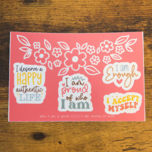 Affirmation Stickers sheet on a wood table. It has 4 positive affirmation stickers and a positive affirmation printed on the sheet at the bottom.