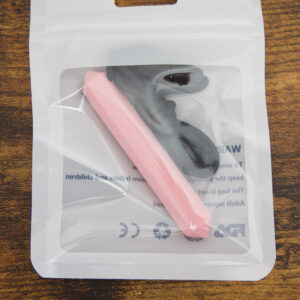 light pink long narrow prism shaped chew necklace inside the packaging on a wood table