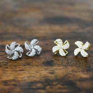 silver windmill earrings and gold windmill earrings both covered in sparkly rhinestones and on a dark rustic wood surface