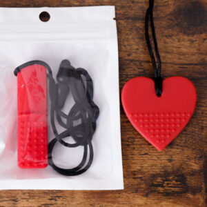 Red bar chew necklace inside the bag packaging, and a red heart chew necklace